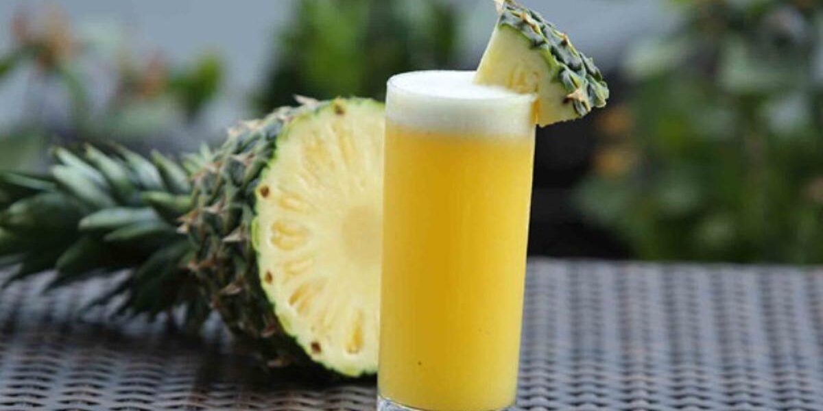 Segelas jus nanas segar dengan tambahan es batu dan hiasan daun mint, sempurna untuk hari yang cerah
